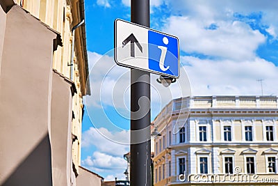 Info sign with a forward/up arrow on a street pole, with city architecture in the back Stock Photo