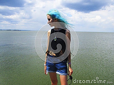 An informal girl in a black top with green hair stands in the wind Stock Photo