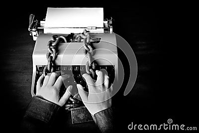 Information censorship - Hands writing on a typewriter locked with a chain Stock Photo