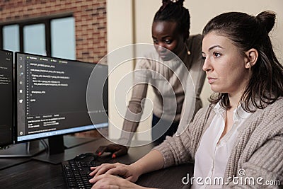 Informational agency multiracial tech engineers programming application while using computer. Stock Photo