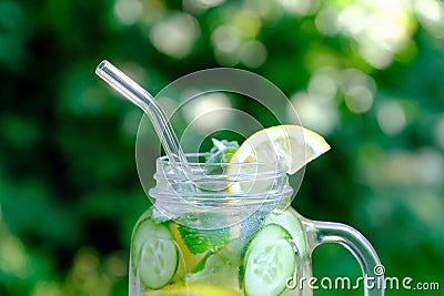 Infused detox water with cucumber, lime and mint in glass jar with drinking straw. Summer cocktail, cool fresh lemonade. Close-up Stock Photo
