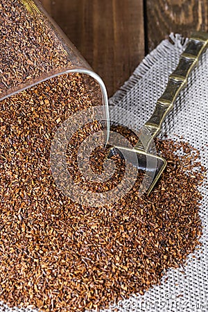 Infuser with dry rooibos leaves on grey wooden table, closeup Stock Photo