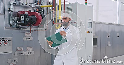 Ingenieur man met een baard in een wit speciaal dansende charismatiek in een grote levensmiddelenfabriek die groot glimlacht stock video Ingenieur man met een baard in een wit speciaal dansende charismatiek in een grote levensmiddelenfabriek die groot glimlacht stock video