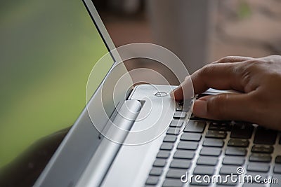 After saving all work Use your finger to press the button to turn off the silver notebook computer Stock Photo
