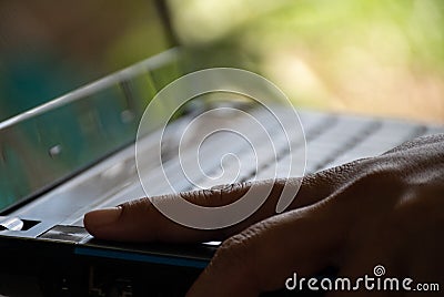 After saving all work Use your finger to press the button to turn off the silver notebook computer Stock Photo