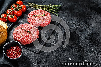 Ingredients for cooking burgers. Minced beef patties, buns, tomatoes, herbs and spices. Black background. Top view. Copy space Stock Photo