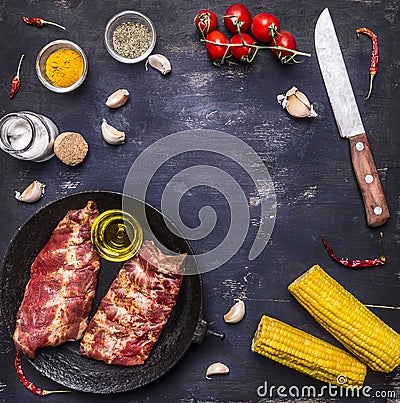 Ingredients for cooking double raw lamb ribs in a cast iron frying pan with vegetables and spices on dark blue wooden rustic back Stock Photo