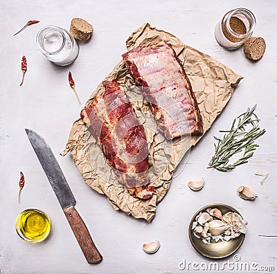 Ingredients for cooking double raw lamb ribs on paper with a knife, garlic, salt, butter and herbs on white wooden rustic backgro Stock Photo