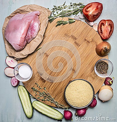 Ingredients for cooking turkey breast with couscous with vegetables and spices on a cutting board round on wooden rustic backgroun Stock Photo