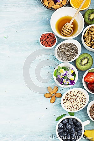 Ingredients for healthy breakfast, nuts, oatmeal, honey, berries, fruits, blueberry, orange, Edible flowers, Chia seeds Stock Photo