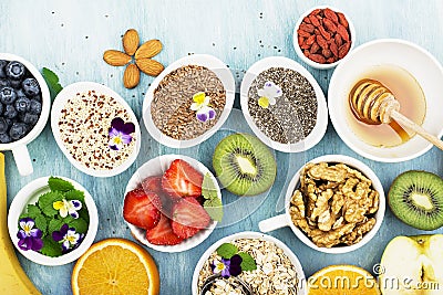 Ingredients for healthy breakfast, nuts, oatmeal, honey, berries, fruits, blueberry, orange, Edible flowers, Chia seeds Stock Photo