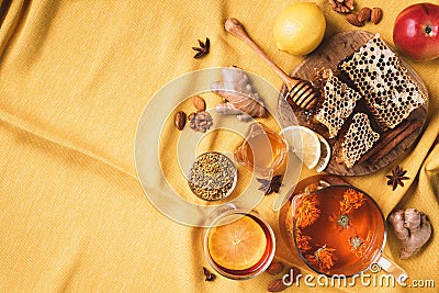 Ingredients for healthy hot drink. Lemon, calendula, ginger, mint, honey, apple and spices over yellow background. Copy space. Top Stock Photo