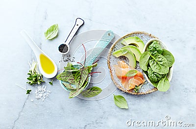 Ingredients for a healthy salad on gray stone background. Smoked salmon, avocado, spinach, sorrel, radis sprouts, black cumin. Stock Photo