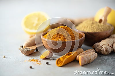 Ingredients for hot ayurvedic drink. Turmeric powder, curcuma root, cinnamon, ginger, lemon over grey background. Copy Stock Photo