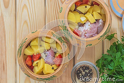 Ingredients for meat and potatoes baked in rustic pots. Cooking raw beef steak on bone on a plate with vegetables. Wood table Stock Photo