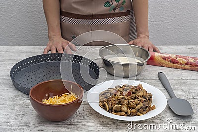 Ingredients for quiche of cheese, mushrooms and bacon on work table on background body and woman hands with blur. Concept of home Stock Photo