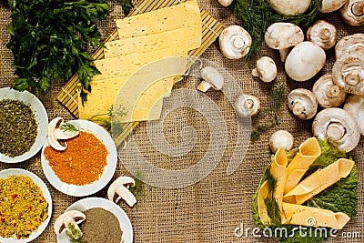 Ingredients. spice, parsley, thin slices of yellow cheese on a green salad sheet and raw champignons on burlap. Stock Photo