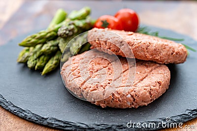 Ingredients for tasty vegan dinner, meat free plants based steak, green asparagus and red tomatoes Stock Photo