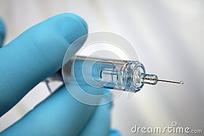 Injection needle held by gloved hand Stock Photo