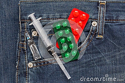 Injection syringe with ampulla and two packaging with pills are lying in side pocket of jeans. Medical health. Stock Photo