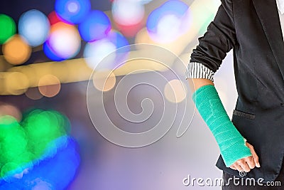 Injured businesswoman with green cast on hand and arm on light b Stock Photo