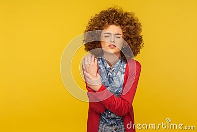 Injured hand. Portrait of woman wincing in pain and touching sore wrist, suffering joint inflammation Stock Photo