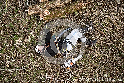 Injured lumberjack with chainsaw lying on the ground after fall Stock Photo