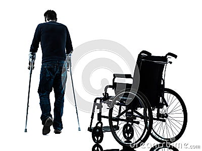 Injured man with crutches walking away from wheelchair silhou Stock Photo