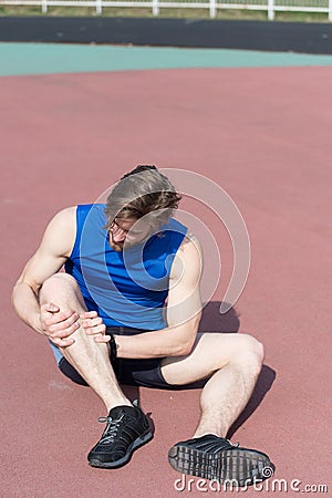 Injured runner on running track feeling pain of broken leg Stock Photo