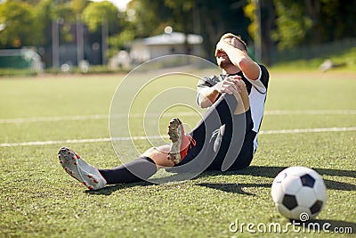 Injured soccer player with ball on football field Stock Photo