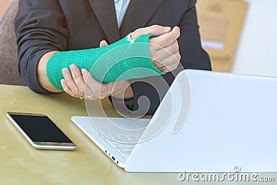 injured woman with broken hand sitting and holding green cast wo Stock Photo