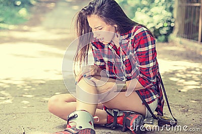 Injured young woman suffering from pain sitting on the ground Stock Photo