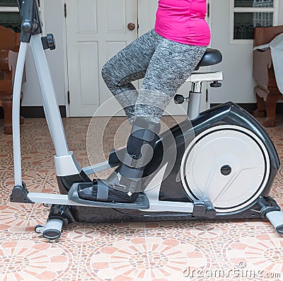 injury woman with black cast on leg sitting on exercise bike at Stock Photo