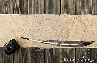 Inkwell, feather and old paper on a wooden background close-up Stock Photo