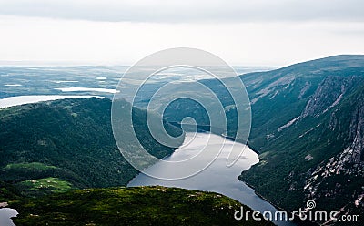 Inland fjord between steep cliffs against green landscape Stock Photo