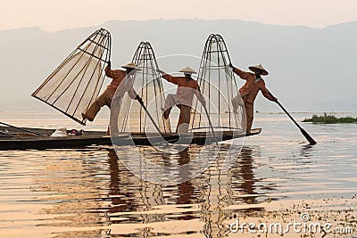 Inle, Myanmar - March 2019: three traditional Burmese leg rowing fishermen at Inle lake Editorial Stock Photo