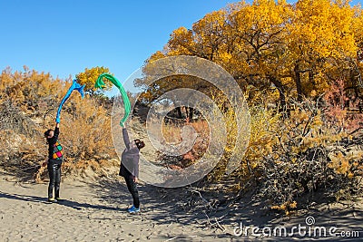 Dancing ladies in forest of populus euphratica in desert Editorial Stock Photo