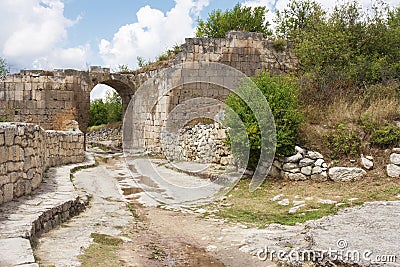 The inner road of the ancient cave city of Chufut Kale, through the arch of the defensive structure, walls Stock Photo