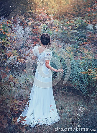 Innocent charming girl in a long white vintage expensive dress got lost in the forest, lost her way, cool colors Stock Photo