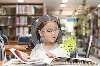 Innovative creative idea for copyrights law concept with kid surprised reading book with lightbulb in library Stock Photo