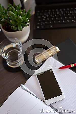 Top view office desk with close up smartphone and paper notebook. Innovative office concept with copy space. Stock Photo