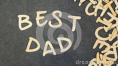 The inscription `best dad` folded of wooden letters on a black table, next to a pile of scattered wooden letters. Stock Photo