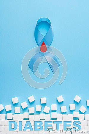 Inscription diabetes blue ribbon awareness with red blood drop and ruined wall made of sugar cubes on a blue background Stock Photo