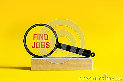 magnifying glass with text find jobs on wooden table Stock Photo