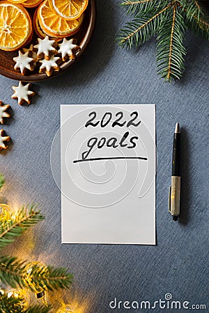 Inscription 2022 GOALS on paper sheet. Winter decoration with dried oranges on blue background. Stock Photo