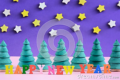 The inscription Happy New Year is made in colorful letters. Small decorative Christmas trees. Stock Photo