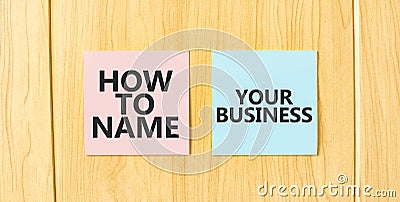 Inscription HOW TO NAME YOUR BUISINESS on pink and blue square sticky sticker on wooden wall Stock Photo