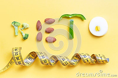 Inscription keto composed of vegetables and measuring tape on yellow background Stock Photo