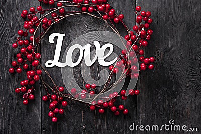 The inscription `Love` on a dark background with red artificial berries with a place for text. Offset focus. Defocus Stock Photo