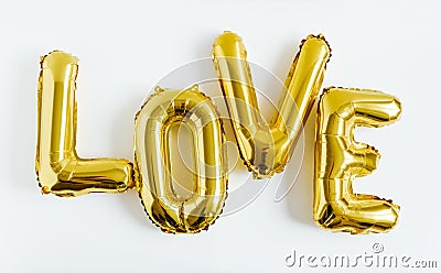 Inscription LOVE foil inflatable golden ballon on the white background. Love, romance and Valentines day concept. Flat lay Stock Photo